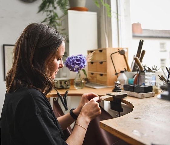 Rhiannon sitting at her jewellery workbench
